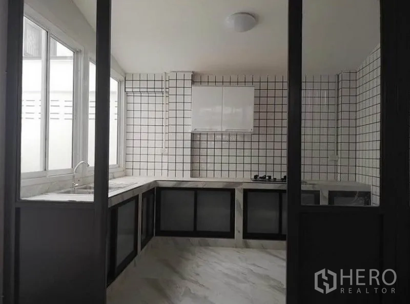 联排别墅 出租或出售在Din Daeng, Bangkok - 封闭式厨房，U形大理石纹台面，方砖墙，燃气灶与大窗户。