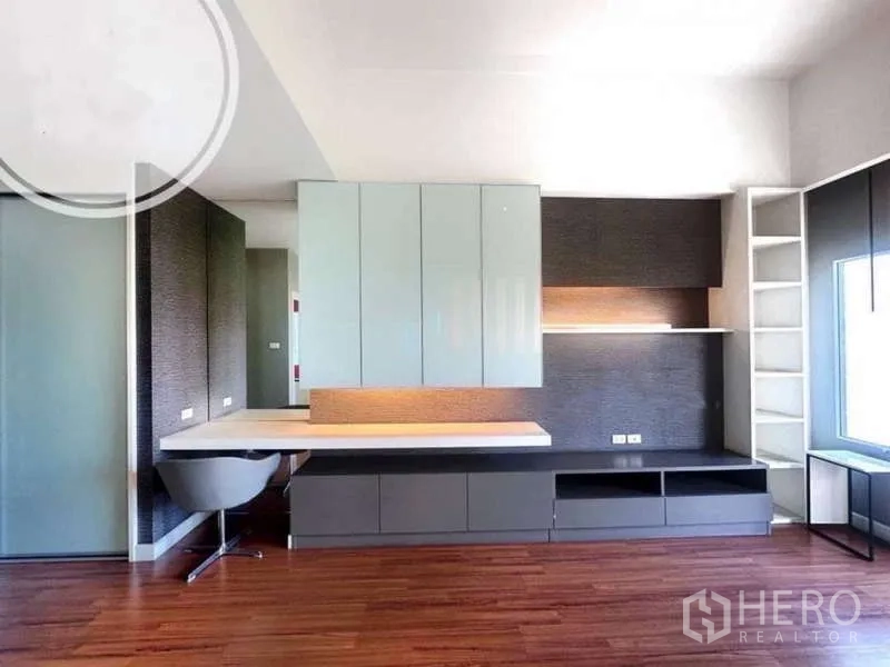 Townhouse for rent in Saphan Sung, Bangkok - Built-in desk and cabinets in a room with wood floors and large window.
