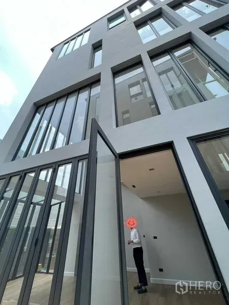 Home Office for sale in Wang Thonglang, Bangkok - Modern multi-storey home office exterior with tall windows and a large pivot door.