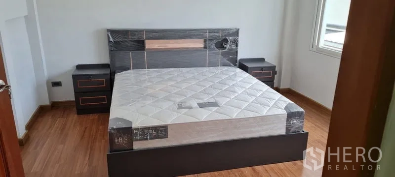 Townhouse for rent in Watthana, Bangkok - Guest bedroom with new mattress, nightstands, and abundant natural light.