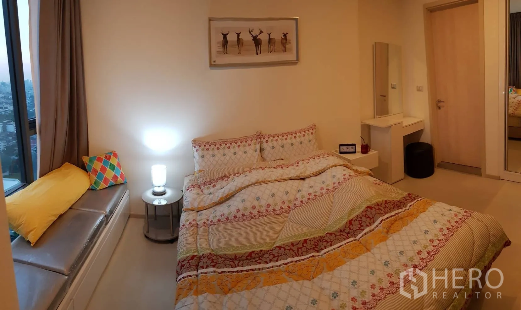 Condominium for rent in Khlong Toei, Bangkok - Cozy bedroom with double bed, window seat, bedside lamp, dressing table, and mirrored wardrobe.