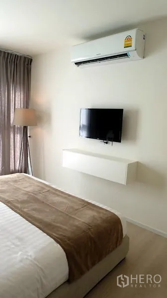 公寓 出售在Khlong Toei, Bangkok - 卧室内墙挂电视与空调，整体配色素雅柔和。