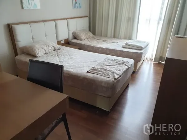 Condominium for rent in Watthana, Bangkok - Second bedroom with twin beds, study desk, wood flooring and sliding glass door to the balcony.