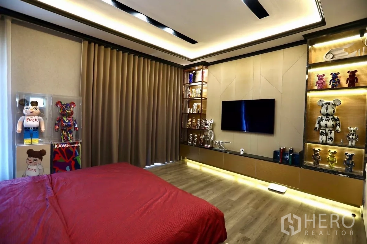 Detached House for rent in Samut Prakan - Second bedroom with wood floors, bold red bedding and full-height curtains.