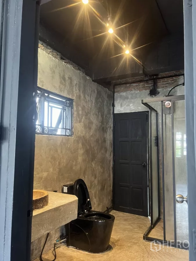 Home Office for rent in Wang Thonglang, Bangkok - Modern bathroom featuring a black toilet, concrete sink, and shower cubicle.