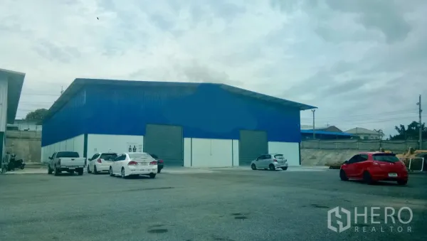 货栈 出租在Si Racha, Chon Buri - 蓝色仓库外观，双卷帘门与宽阔停车及货车通道