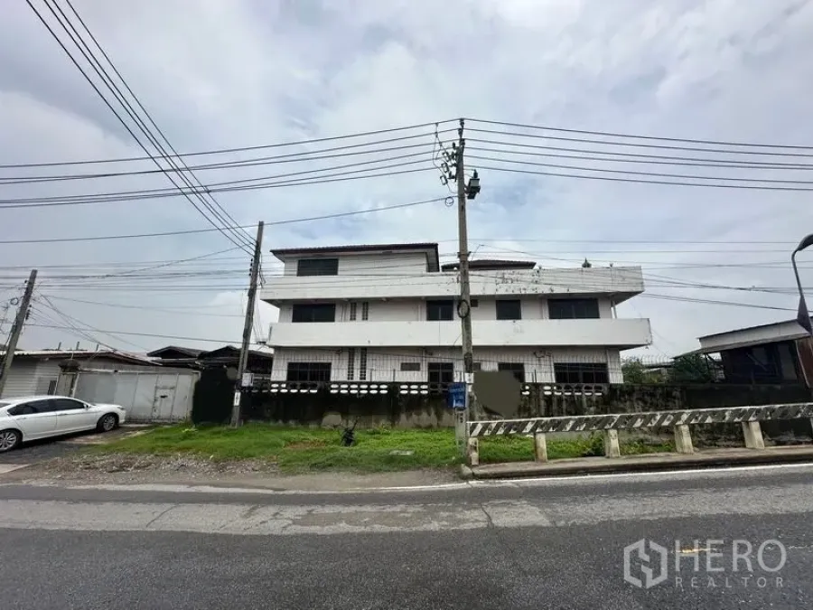 Home Office for sale in Phra Pradaeng, Samut Prakan - Front elevation of the three-storey building behind a walled fence.