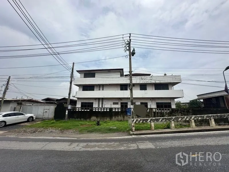 Home Office for sale in Phra Pradaeng, Samut Prakan - Front elevation of the three-storey building behind a walled fence.