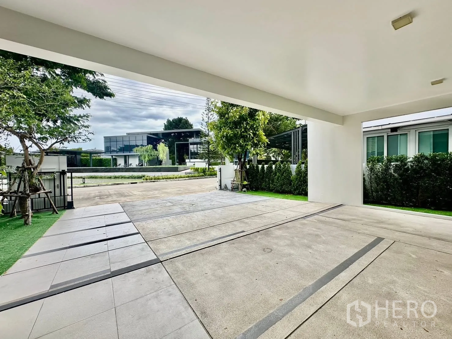 บ้านเดี่ยว for rent in Bang Phli, Samut Prakan - พื้นที่จอดรถในร่มมองออกไปยังหน้าบ้านและอาคารสมัยใหม่ฝั่งตรงข้าม.