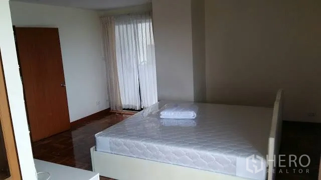 Condominium for rent in Watthana, Bangkok - Spacious bedroom with double bed, sheer curtains, and parquet floor.