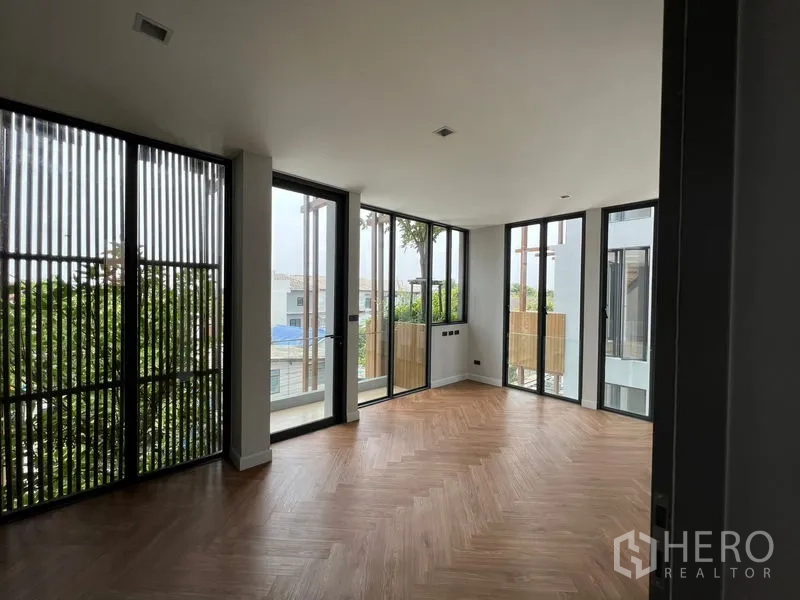 Home Office for sale in Wang Thonglang, Bangkok - Corner room with herringbone wood flooring, sliding glass doors, and balcony screens bringing in natural light.