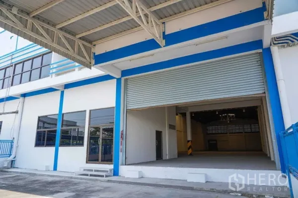 Factory for rent in Bang Sao Thong, Samut Prakan - Factory exterior with covered loading bay and wide roller shutter door for trucks.