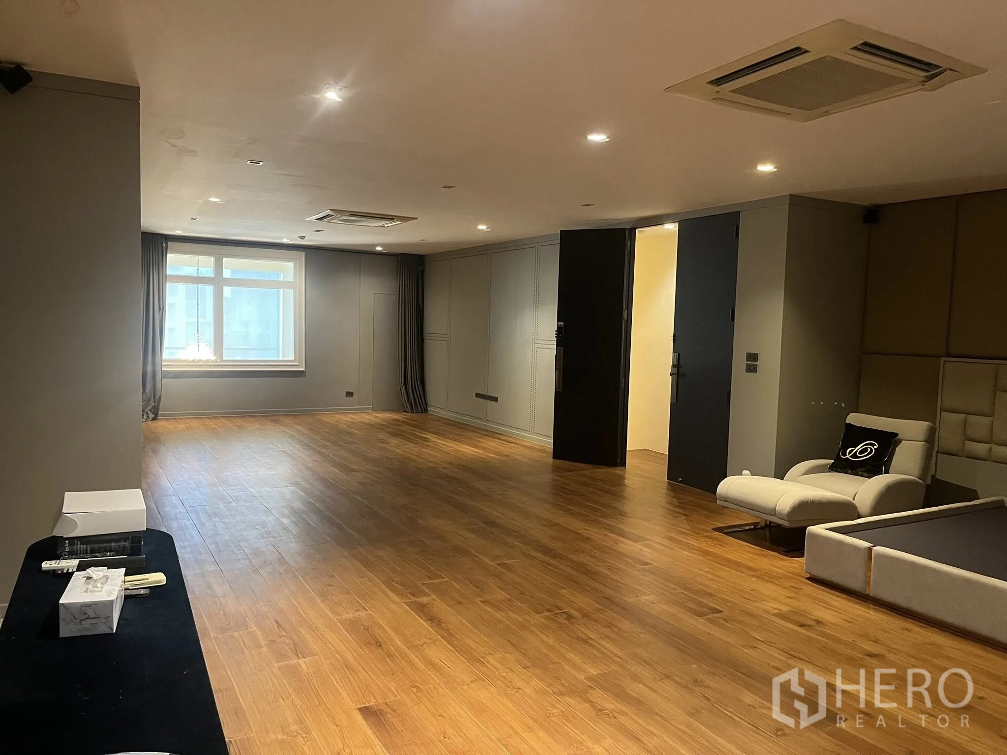 Home Office for rent in Watthana, Bangkok - Expansive multipurpose room with wood floors, window, and recessed lights.