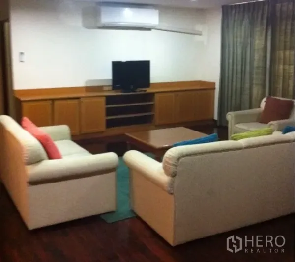 Condominium for rent in Watthana, Bangkok - Cozy living room with cream sofas, TV on a low wooden console, and hardwood floors.
