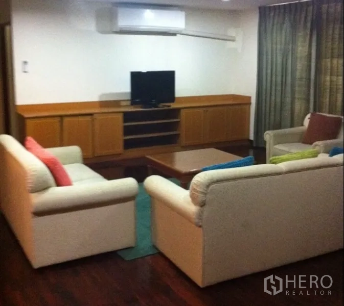 Condominium for rent in Watthana, Bangkok - Cozy living room with cream sofas, TV on a low wooden console, and hardwood floors.