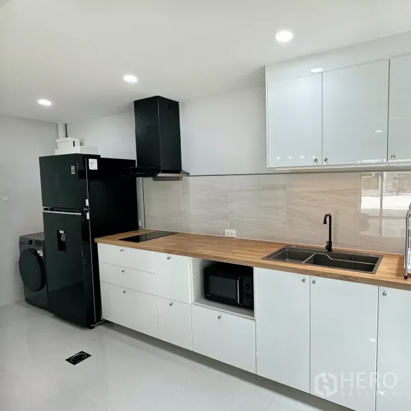 Townhouse for rent in Bang Phli, Samut Prakan - White linear kitchen with wood countertops and ample cabinetry.