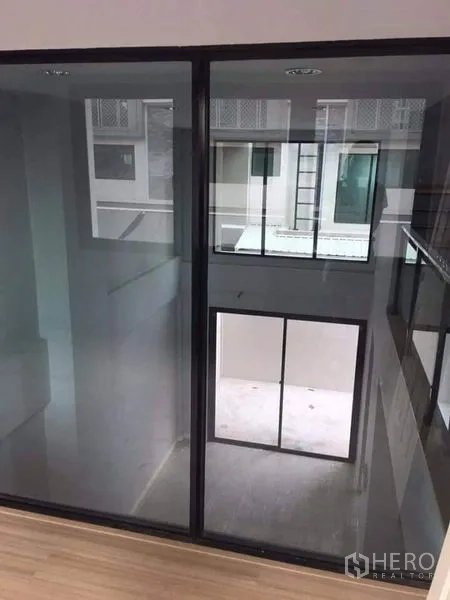 Townhouse for sale in Yan Nawa, Bangkok - Interior atrium with floor-to-ceiling glass panels and sliding doors between levels.