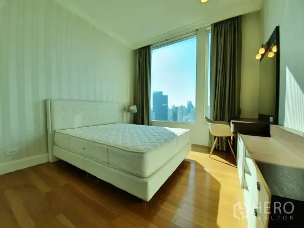 公寓 出租在Watthana, Bangkok - 采光充足的卧室，白色床、木地板、梳妆台与大窗户城市景观。