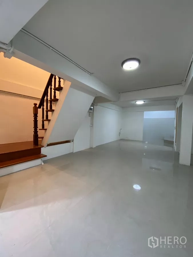 Detached House for rent in Bang Na, Bangkok - Wooden staircase beside the open living area with neutral walls and recessed lighting.