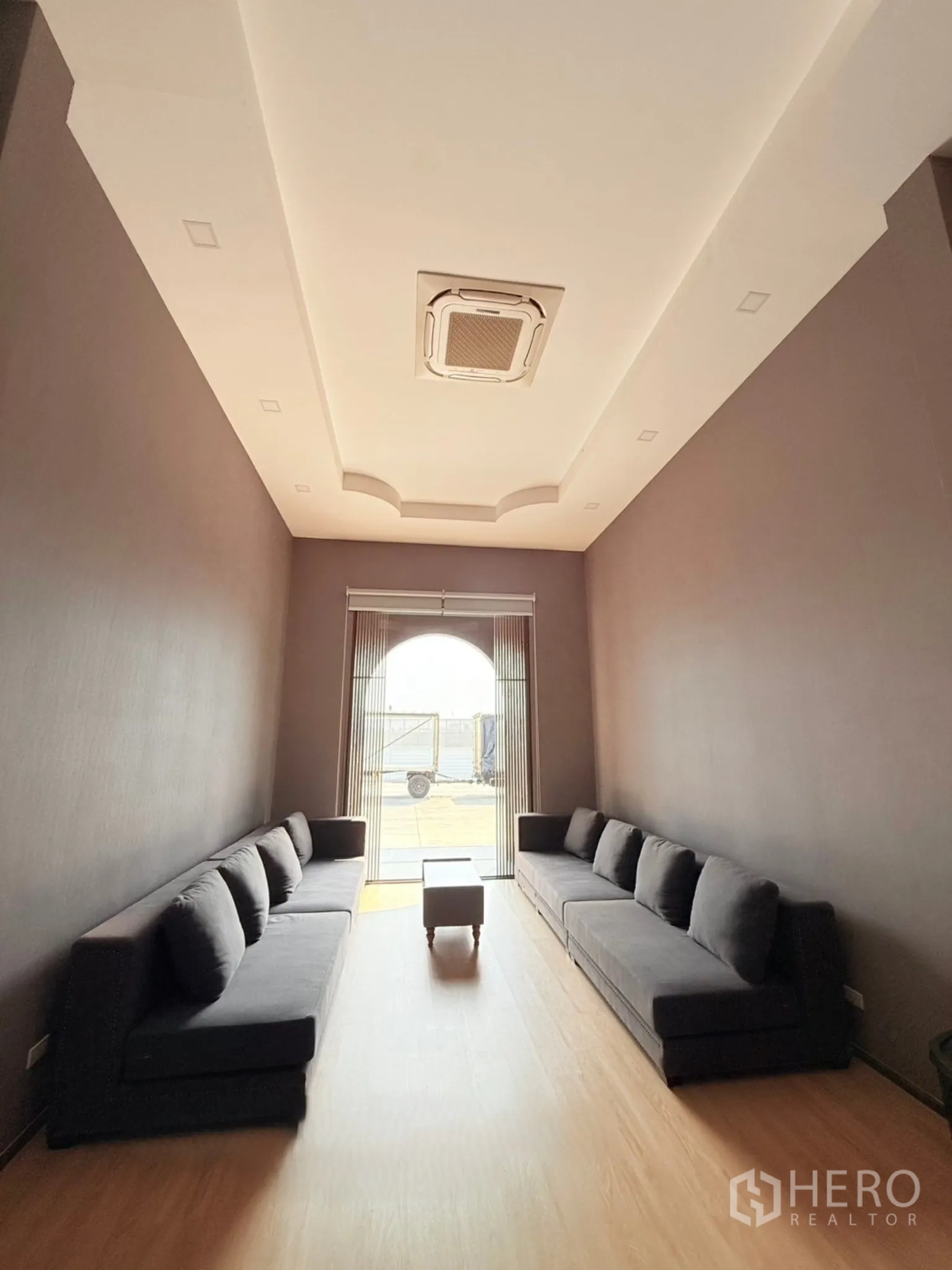 Factory for sale in Ban Bueng, Chon Buri - Office lounge with two gray sofas, wood flooring, and cassette air-conditioning on the ceiling.