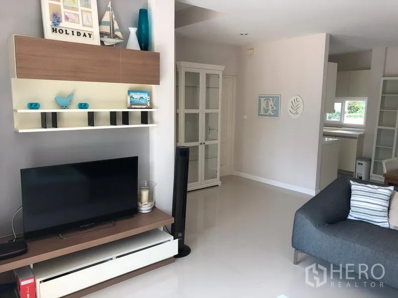 Detached House for rent in Bang Kapi, Bangkok - Living room media wall with built-in shelving and TV on glossy white flooring.