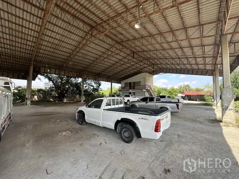 工厂 出租在Phra Nakhon Si Ayutthaya - 高挑钢结构屋棚内停有皮卡，后方有小型办公楼。