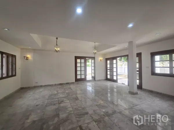 独立式住宅 出租在Phra Khanong, Bangkok - 开放式起居空间，大理石地砖、法式玻璃门通向露台与吊灯