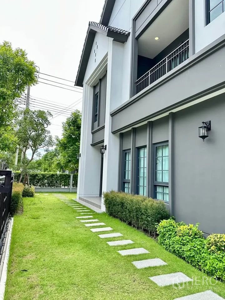 Detached House for rent in Bang Phli, Samut Prakan - Side garden with green lawn, stepping stones, and shrubs along the house.