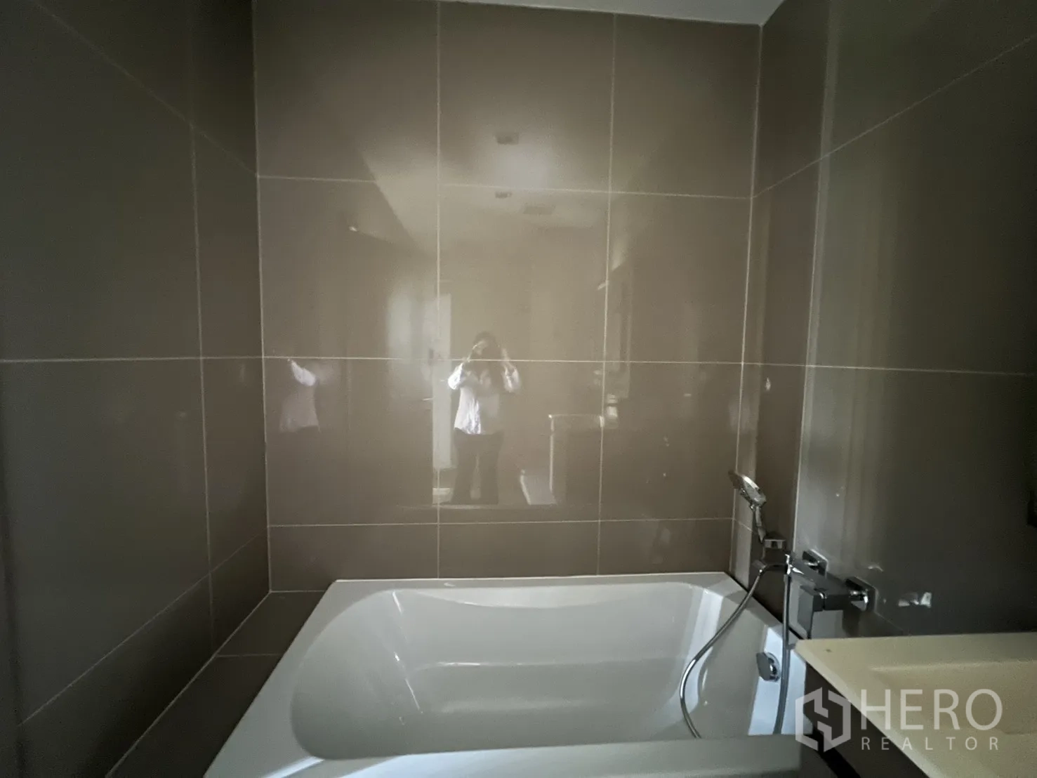 Condominium for rent in Watthana, Bangkok - Bathtub with handheld shower set against dark tiled walls.