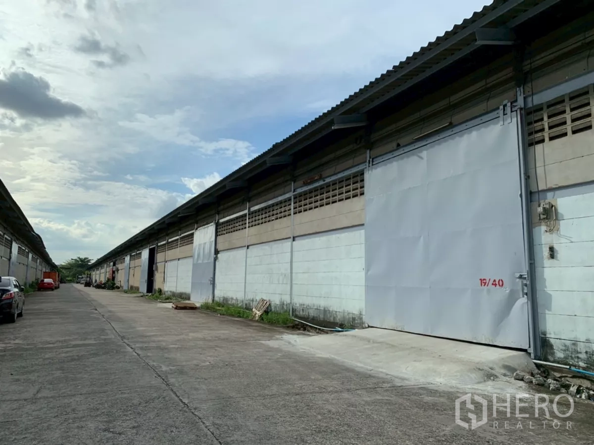 คลังสินค้า ให้เช่าในBang Phli, Samut Prakan - ด้านหน้าโกดังเรียงเป็นแนว ประตูเหล็กบานเลื่อน และถนนภายในกว้างสำหรับรถบรรทุก