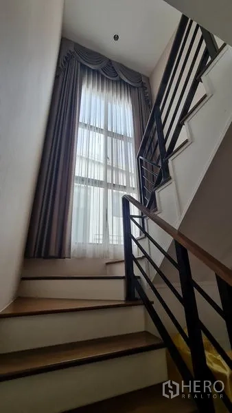 独立式住宅 出售在Samut Prakan - 带金属扶手的楼梯，超高窗户引入自然光。