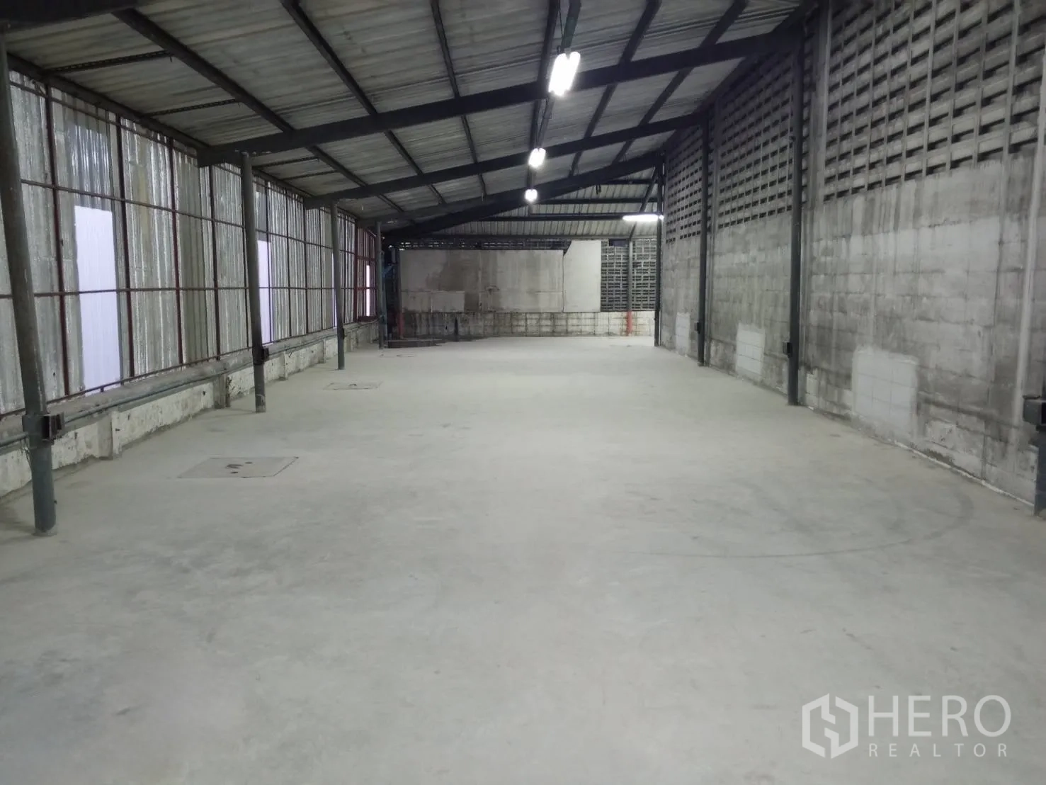 Warehouse for rent in Min Buri, Bangkok - Long warehouse bay with concrete floor, steel truss roof and strip lighting along the ceiling.