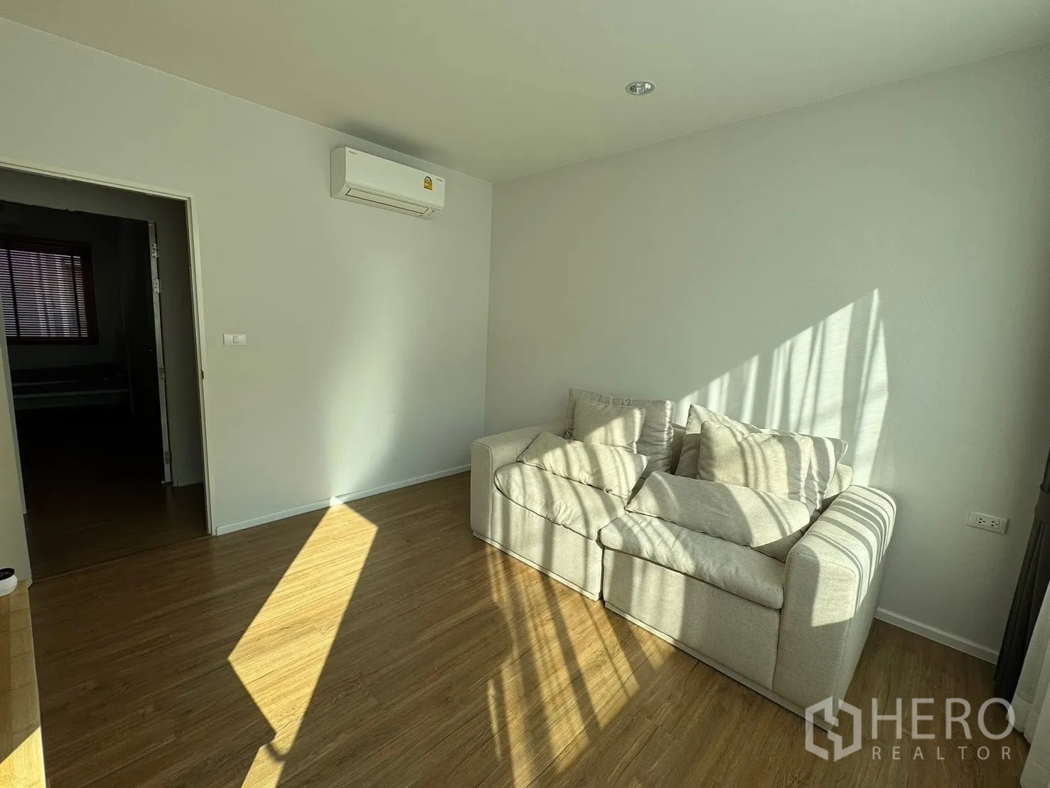 Townhouse for rent in Saphan Sung, Bangkok - Sunny living area with beige sofa on wood floors.