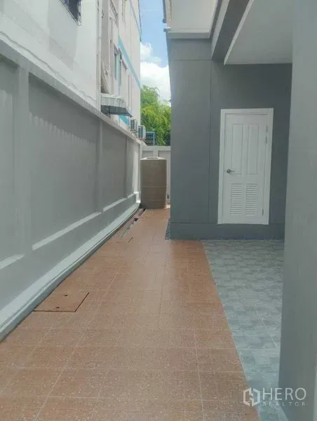 บ้าน ขายในPhra Khanong, Bangkok - ทางเดินข้างบ้านปูกระเบื้อง พร้อมกำแพงสูงและประตูห้องเอนกประสงค์สีขาว