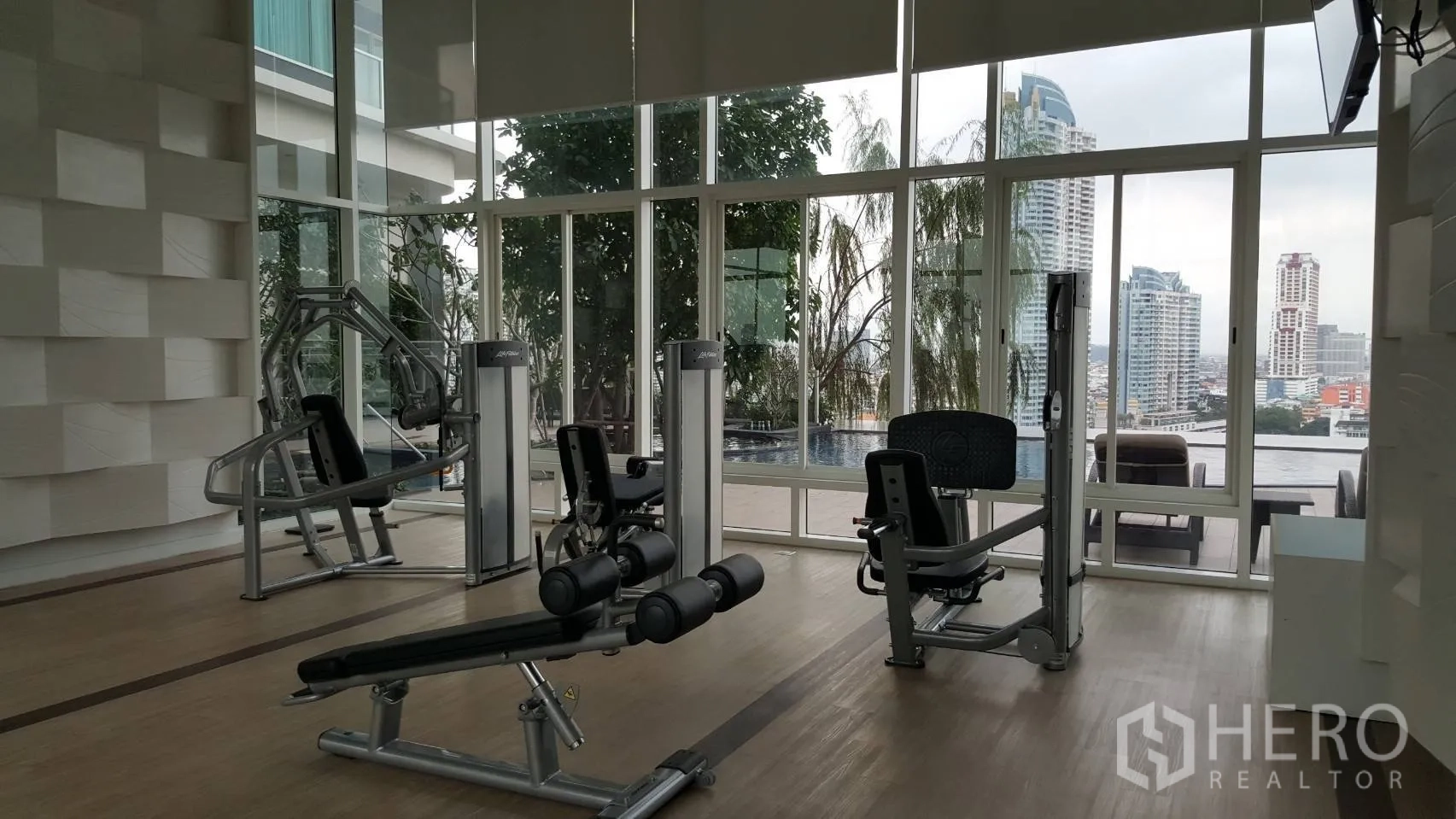 Condominium for rent in Bang Kho Laem, Bangkok - Fully equipped gym with strength machines and wide city views through large windows at the condominium.