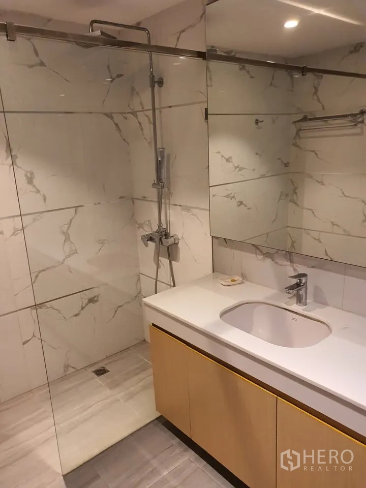 คอนโด for rent in Watthana, Bangkok - ห้องน้ำพร้อมกระจกกั้นอาบน้ำ เคาน์เตอร์ยาว และผนังลายหินอ่อน