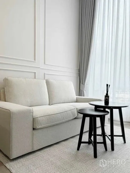 คอนโด ให้เช่า - โซฟาสีขาวกับโต๊ะกาแฟข้างผ้าม่านโปร่งแบบเต็มบาน.