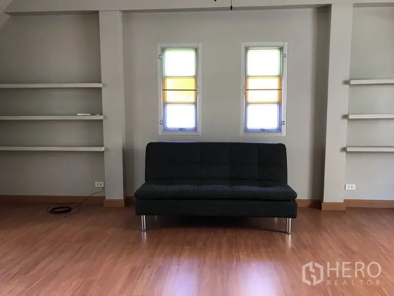 บ้าน ให้เช่าในKhlong Toei, Bangkok - ห้องอเนกประสงค์ขนาดใหญ่ โซฟาสีเข้มและชั้นวางผนัง