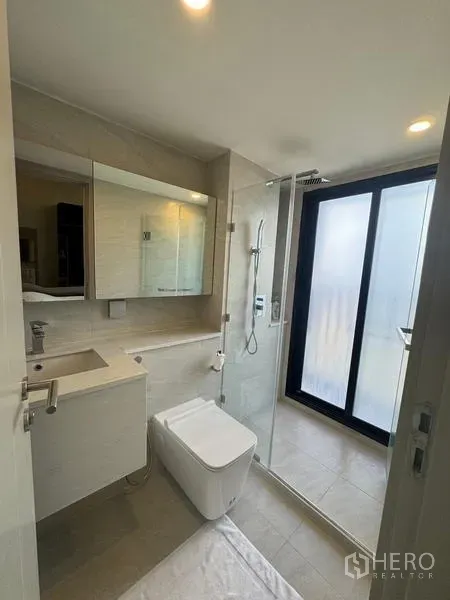 公寓 出租在Ratchathewi, Bangkok - 现代卫浴，带洗手台、玻璃淋浴间与磨砂阳台门。