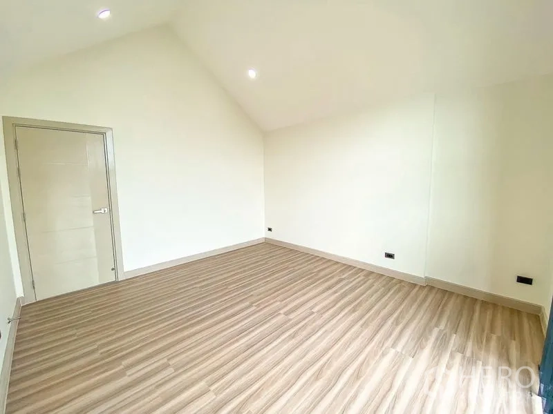 带办公室的家 出租或出售在Bang Na, Bangkok - 宽阔木地板房间，斜顶设计与白色室内门。