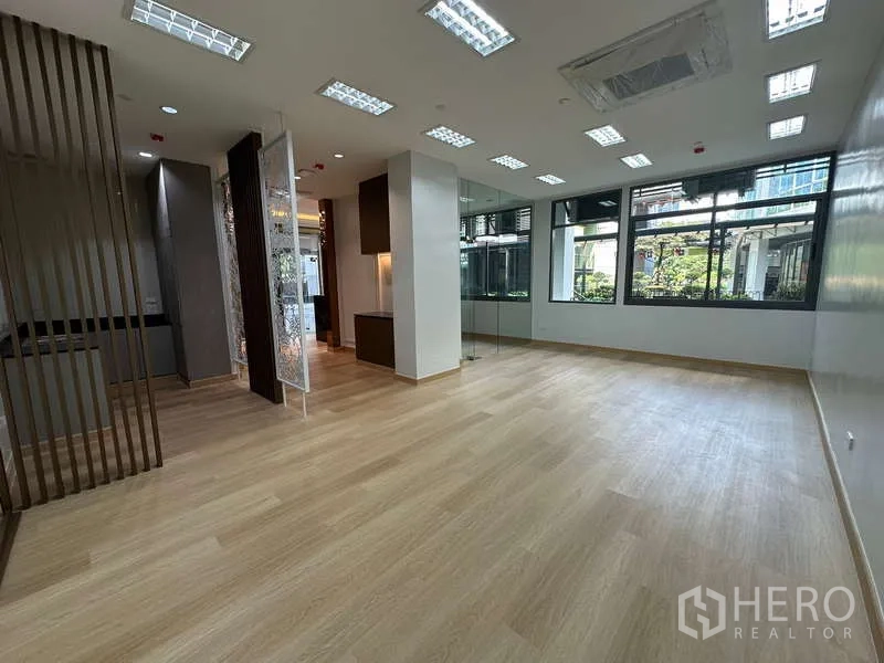 Office Space for rent - Spacious work area with multiple ceiling lights, large windows and glass partition.