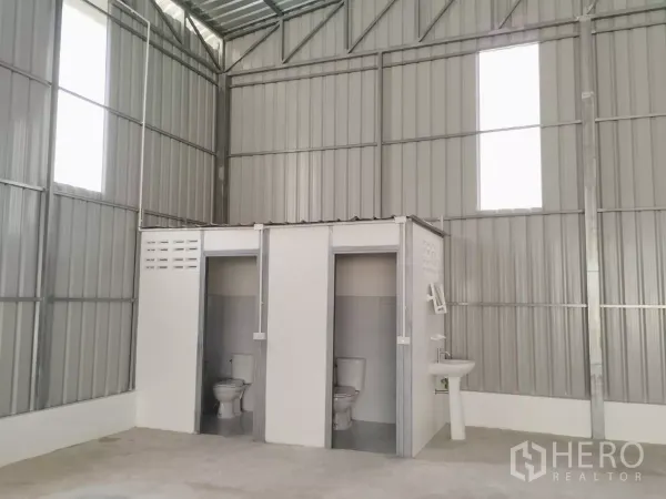 Warehouse for rent in Sai Mai, Bangkok - Internal restroom block featuring two toilets and a sink inside the warehouse.