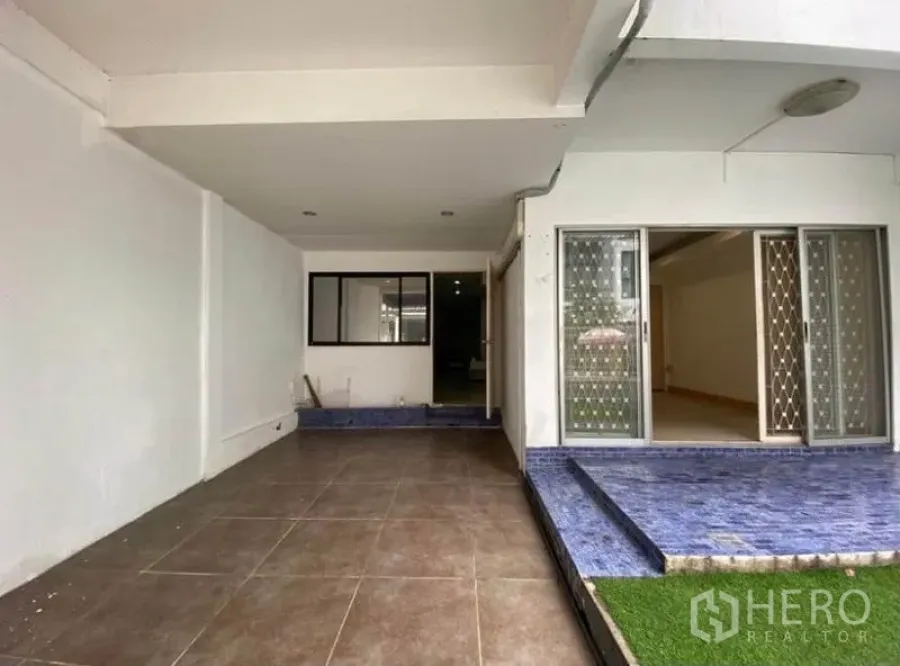 ทาวน์เฮาส์ ให้เช่าในKhlong Toei, Bangkok - ที่จอดรถในร่มและลานหน้าบ้าน พร้อมประตูบานเลื่อนและขั้นกระเบื้องสีน้ำเงินของทาวน์เฮ้าส์ในกรุงเทพฯ