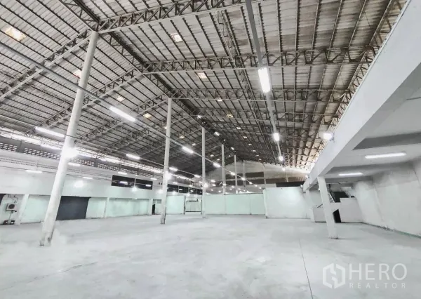 工厂 出售在Samut Prakan - 宽阔厂房内景，高钢架屋顶、明亮LED照明与混凝土地面。