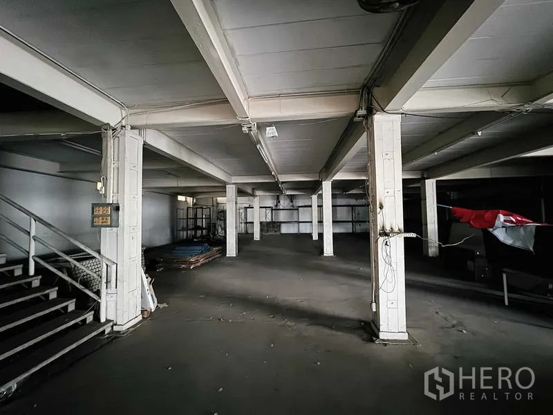 展厅 出租在Min Buri, Bangkok - 底层开放式空间，混凝土柱与楼梯，适合仓储或陈列。