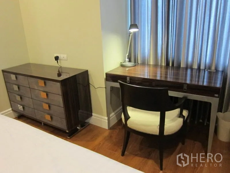 คอนโด ให้เช่าในKhlong Toei, Bangkok - มุมทำงานใกล้หน้าต่าง โต๊ะไม้ เก้าอี้ และโคมไฟอ่านหนังสือ ข้างตู้ลิ้นชัก