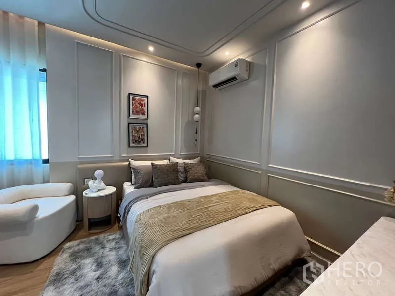 Detached House for sale in Saphan Sung, Bangkok - Guest bedroom with warm paneled walls, accent armchair and soft rug.