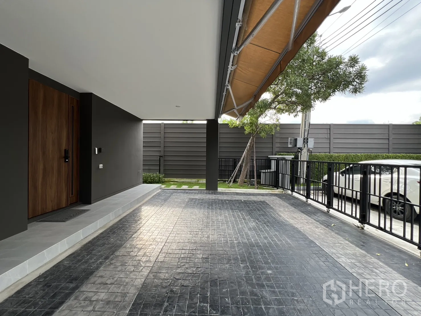 Detached House for rent in Prawet, Bangkok - Covered carport with wood front door and tiled driveway.