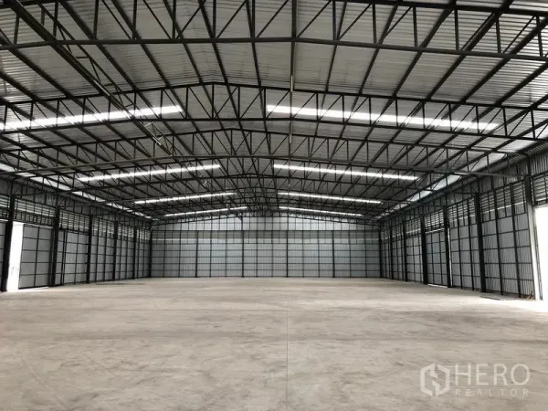 Warehouse for rent in Pathum Thani - Clear-span warehouse hall with exposed steel beams, ridge skylights, and an expansive open floor.