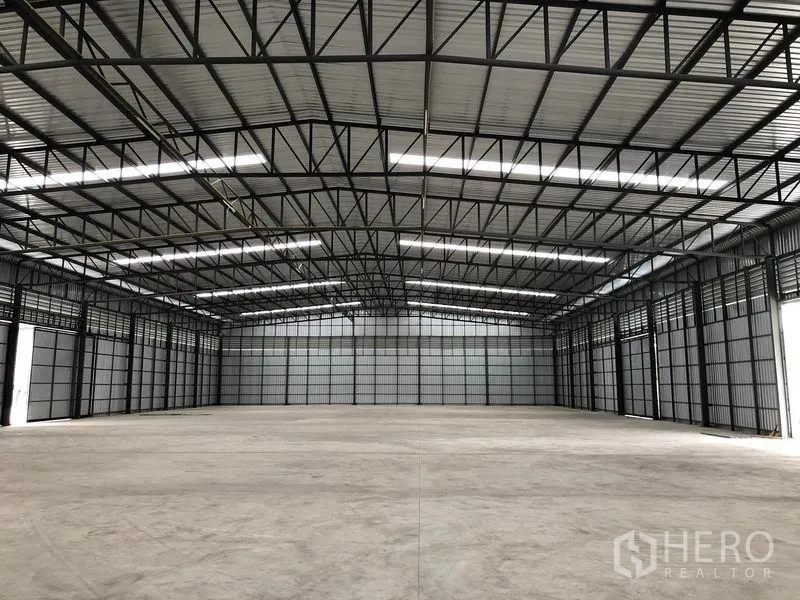 Warehouse for rent in Pathum Thani - Clear-span warehouse hall with exposed steel beams, ridge skylights, and an expansive open floor.